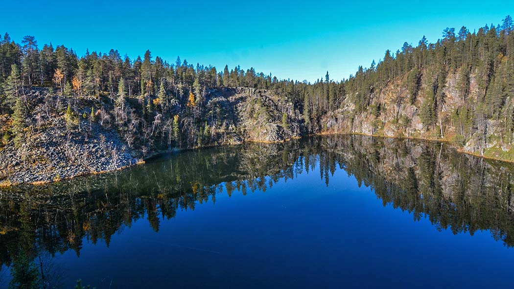 Kirkas järvi. Taustalla kohoavat kalliot jossa havumetsää.