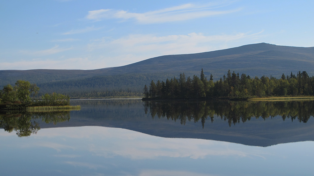 Järven pintaan heijastuu vastarannalla oleva tunturi. Järveä ympäröi havumetsä.