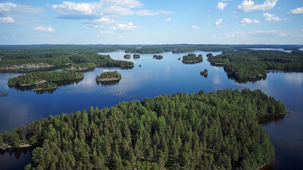 Ilmakuvaa järvimaisemasta, jossa paljon metsäisiä saaria. Useiden saarten rannat ovat kallioisia.