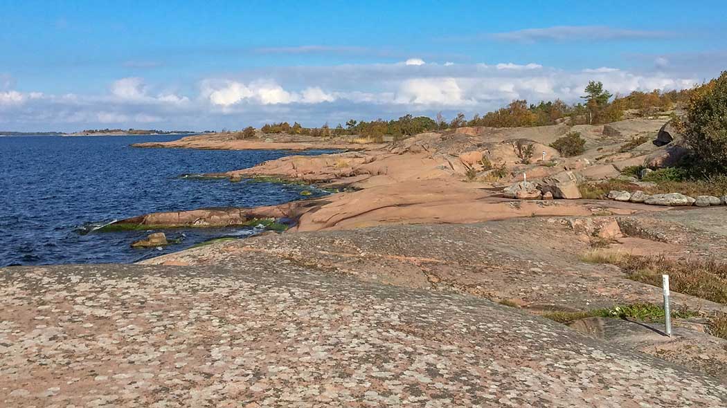 Kesäinen-syksyinen maisema. Meri ja pitkälle jatkuva rantakallio.